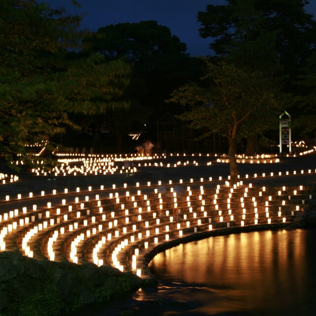 薄暗い夕方の公園にキャンドルがたくさん並べられている様子